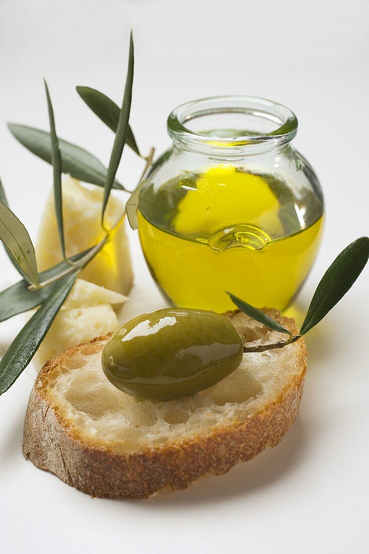 Green olive with twig on white bread, Parmesan, olive oil