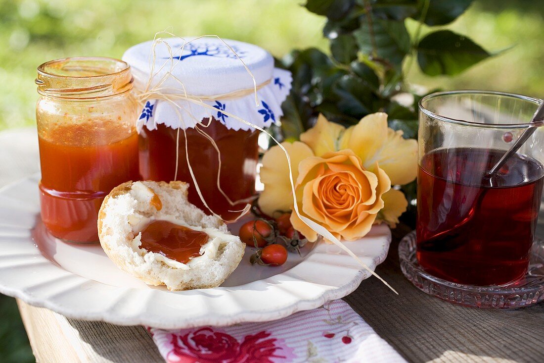 Hagebuttenmarmelade in Gläsern und auf Brötchen