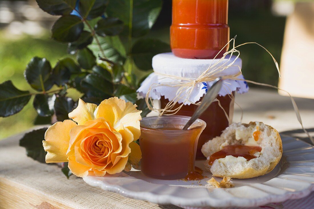 Hagebuttenmarmelade in Gläsern und auf Brötchen