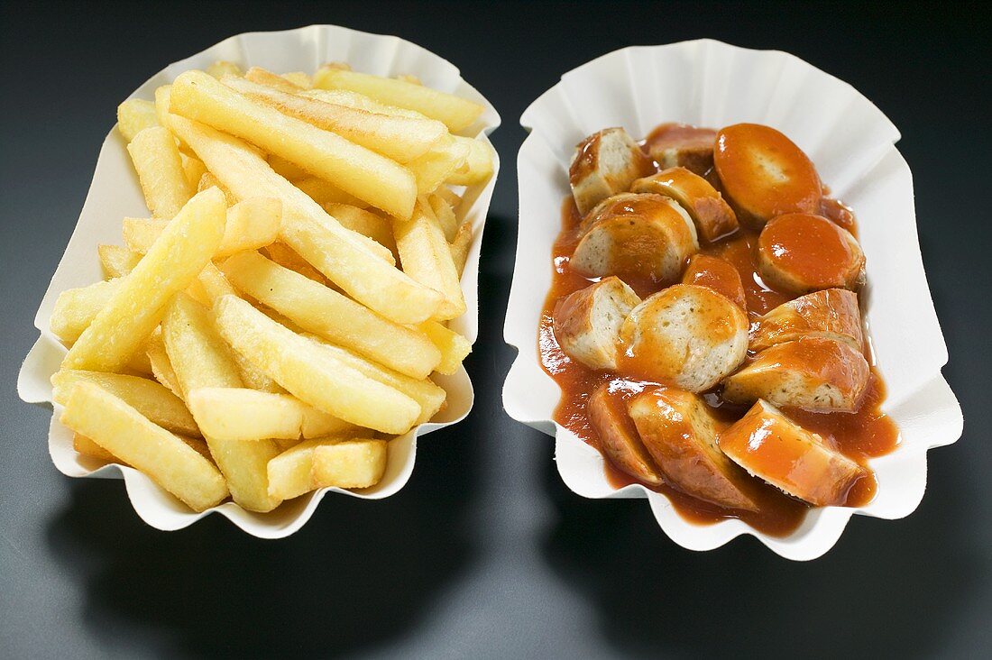 Bratwurst mit Ketchup und Pommes frites auf Papptellern