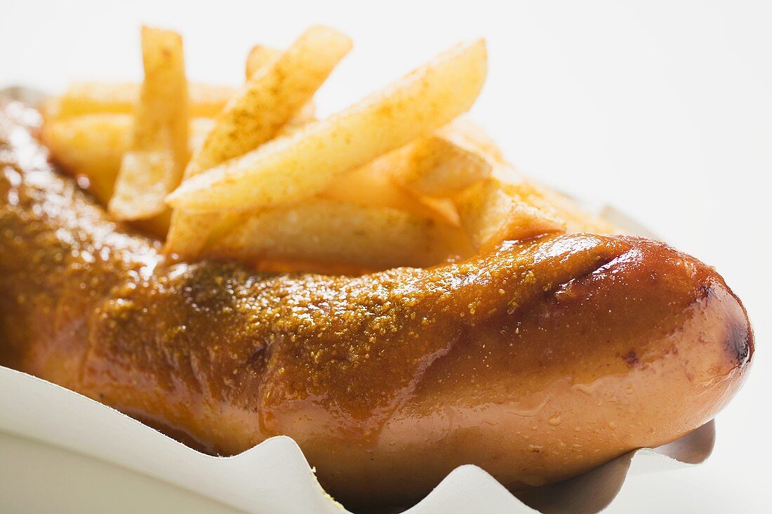 Currywurst mit Pommes frites auf Pappteller (Close Up)