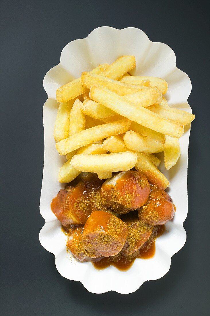 Currywurst mit Ketchup und Pommes frites auf Pappteller