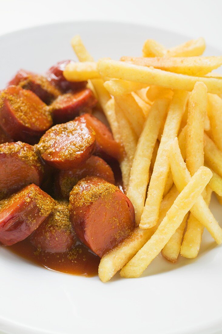 Currywurst mit Ketchup und Pommes frites auf Teller