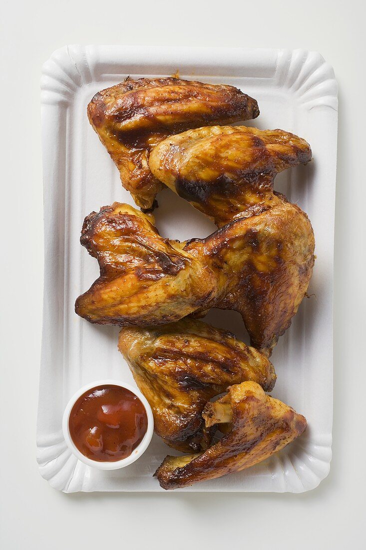 Grilled chicken wings with ketchup on paper plate