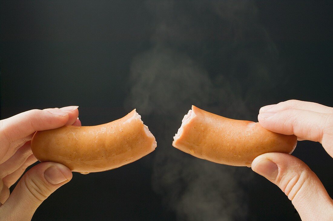 Hand holding a halved frankfurter