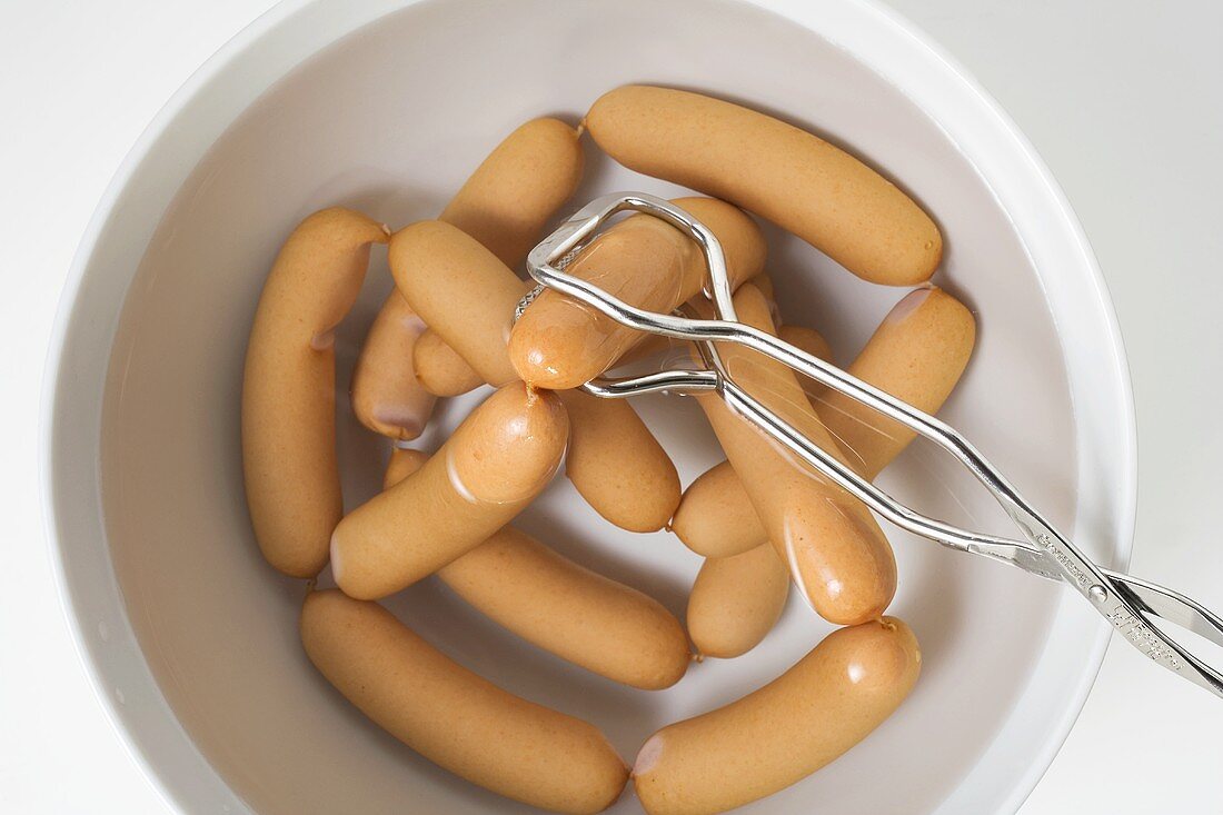 Lifting frankfurters out of water with tongs