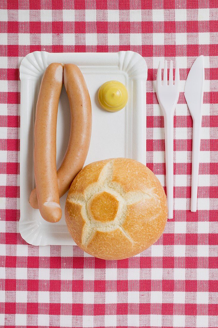 Wiener Würstchen mit Senf und Brötchen auf Pappteller