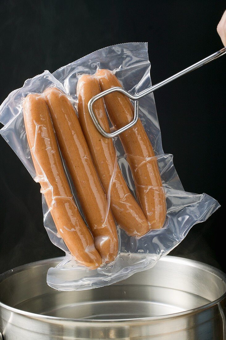 Verpackte Wiener Würstchen in Kochtopf geben