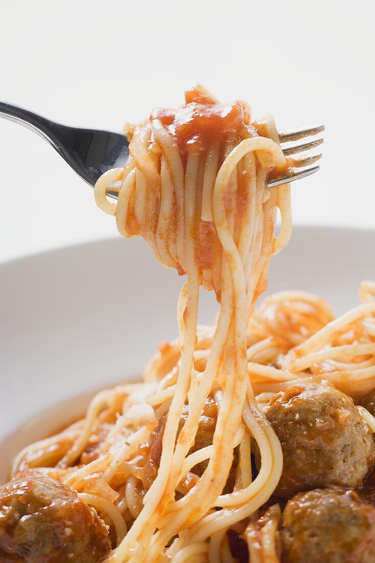 Spaghetti with meatballs and tomato sauce on fork