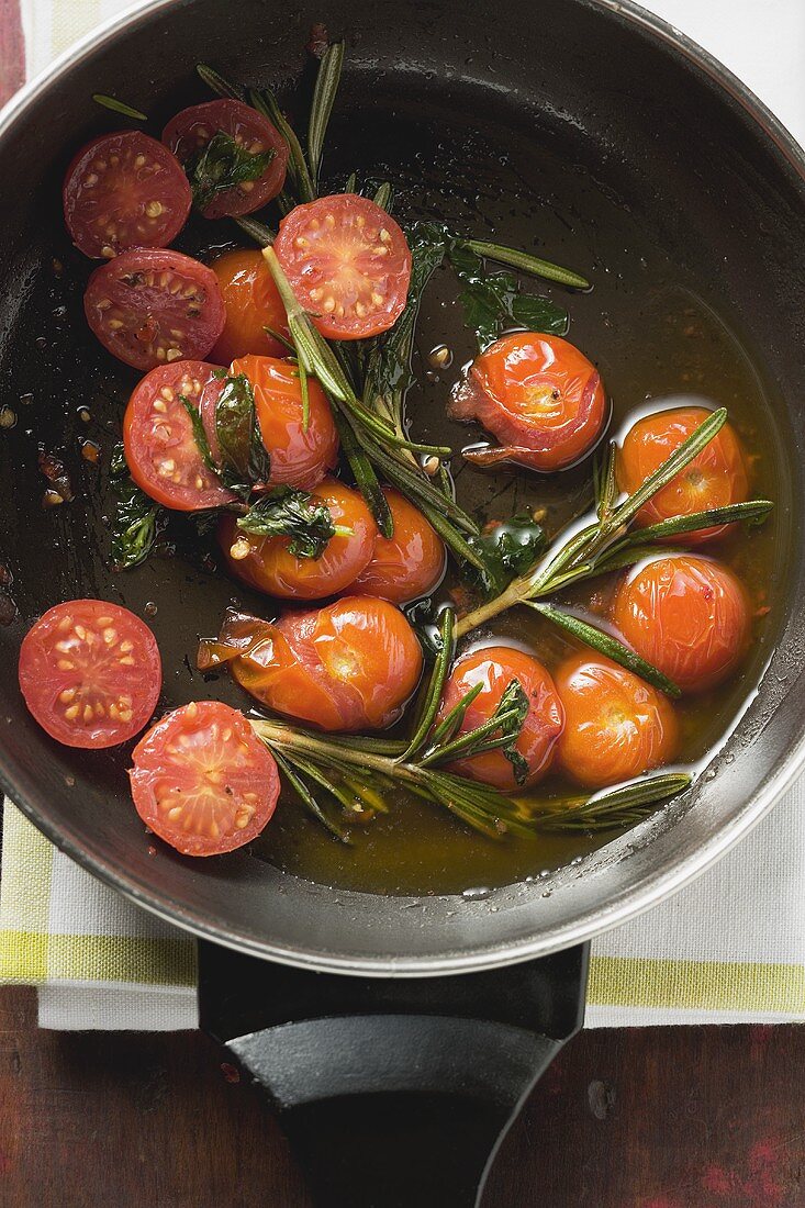 Fried cherry tomatoes with rosemary in frying pan