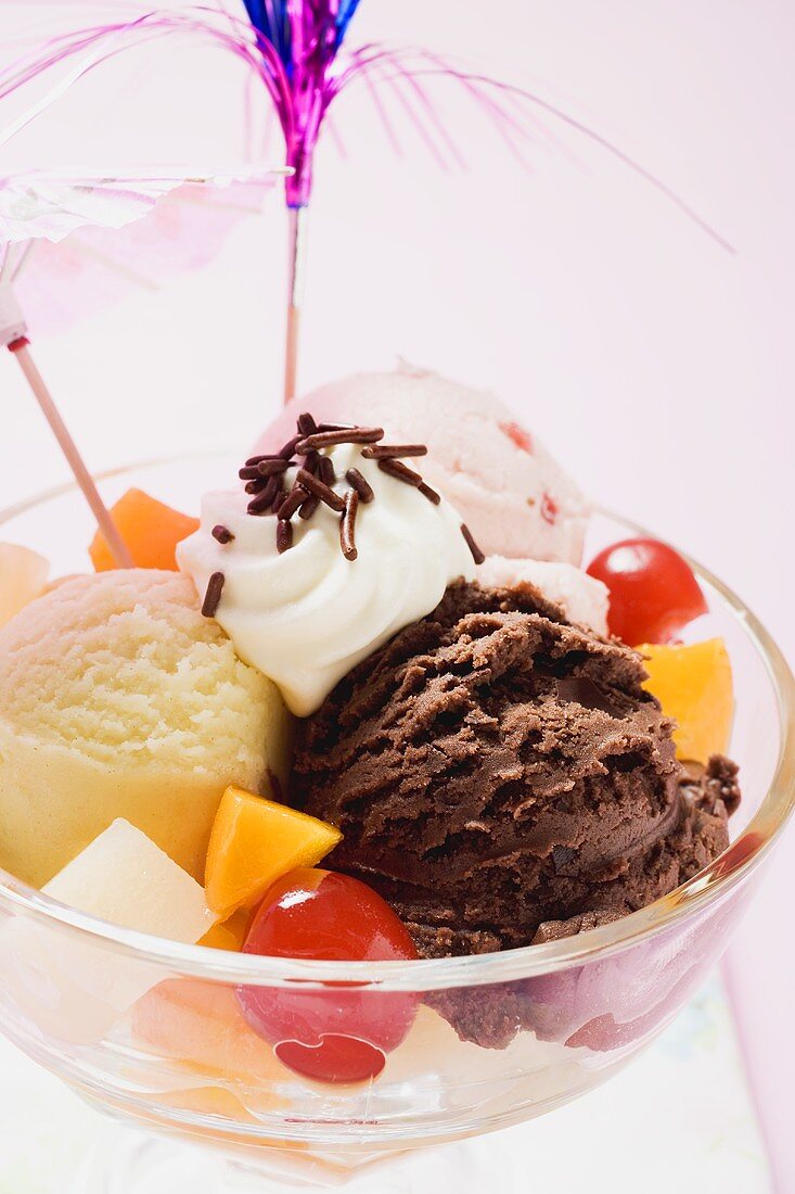 Mixed ice cream with fruit, cream and cocktail umbrella