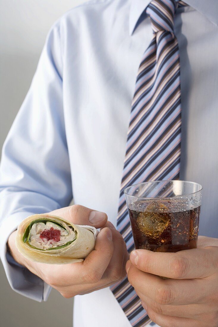 Mann mit Krawatte hält Wrap und Cola