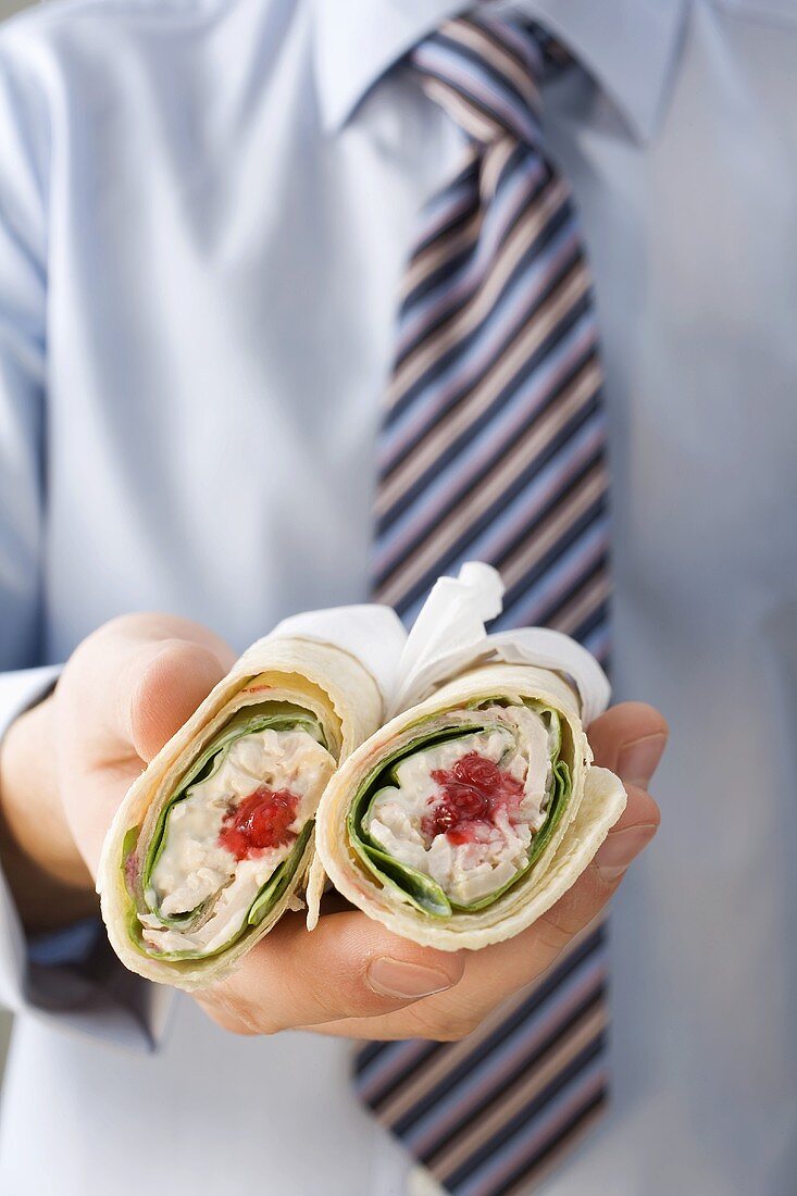 Mann mit Krawatte hält zwei Wraps