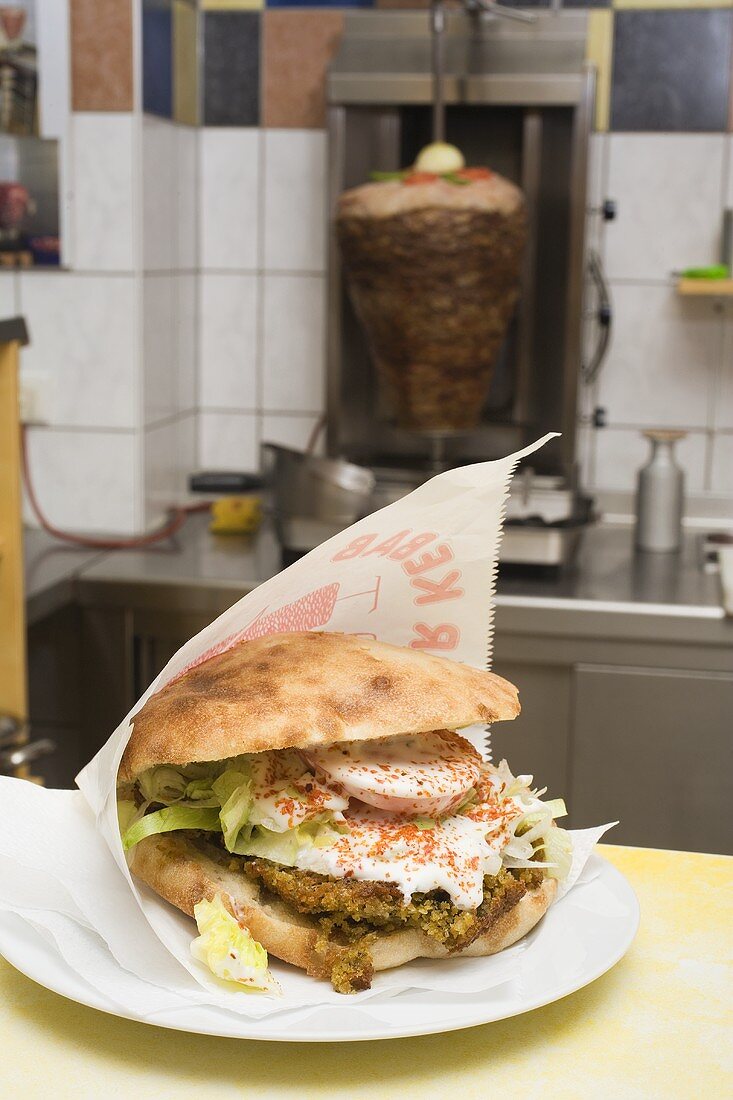 Pita bread with falafel on counter in front of döner grill