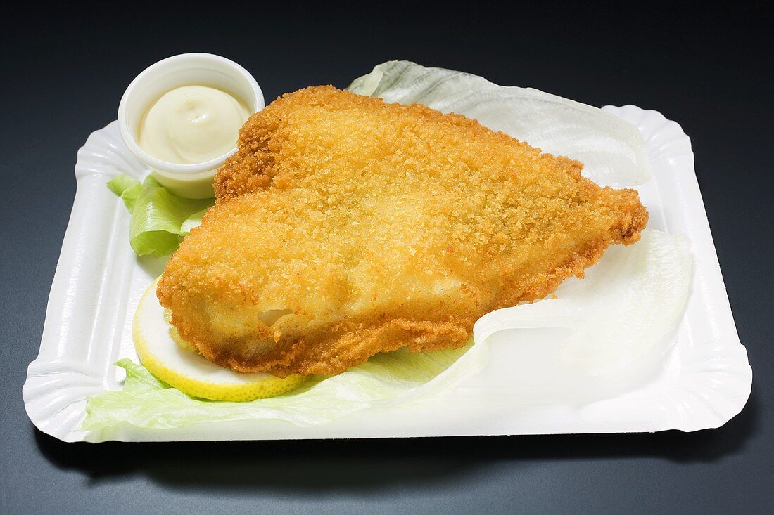 Breaded fish fillet with mayonnaise on paper plate