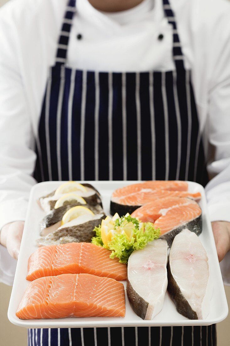 Person hält Tablett mit Lachs- und Wolfsbarschstücken