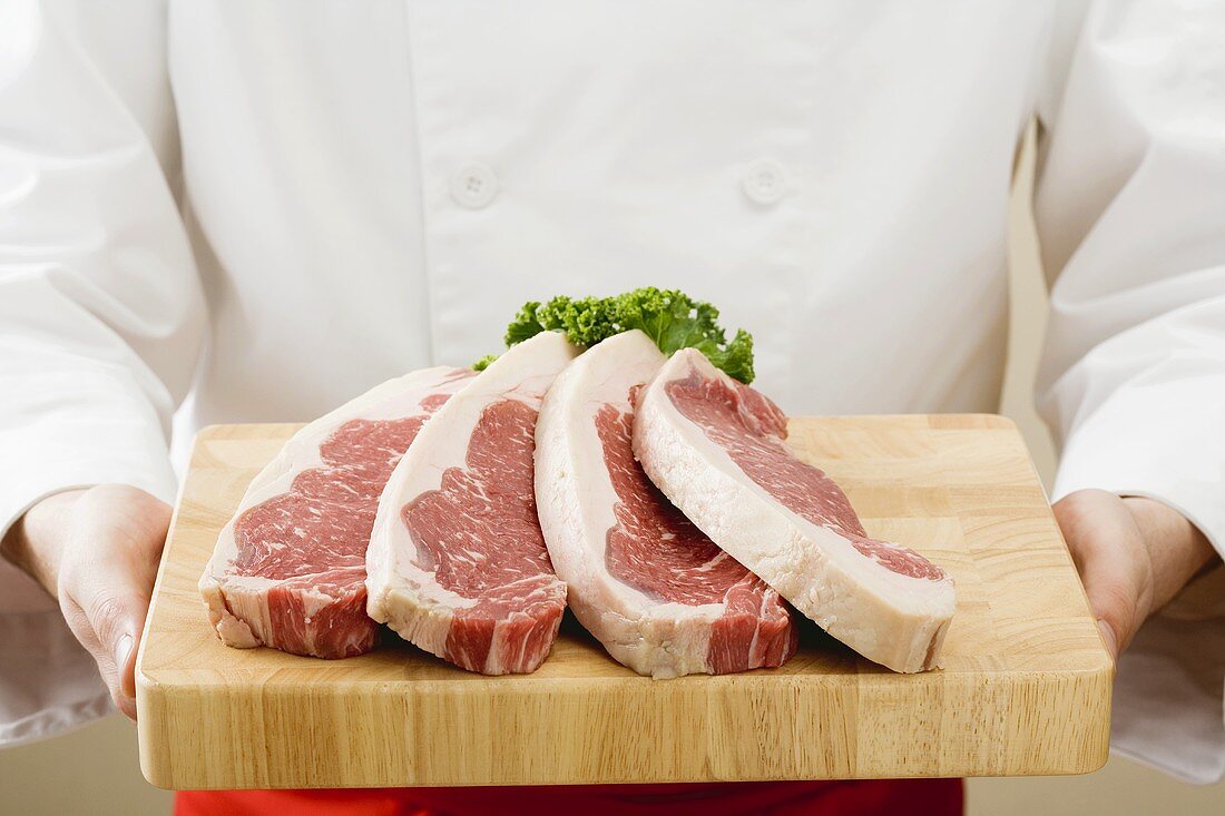 Chef holding sirloin steaks on chopping board