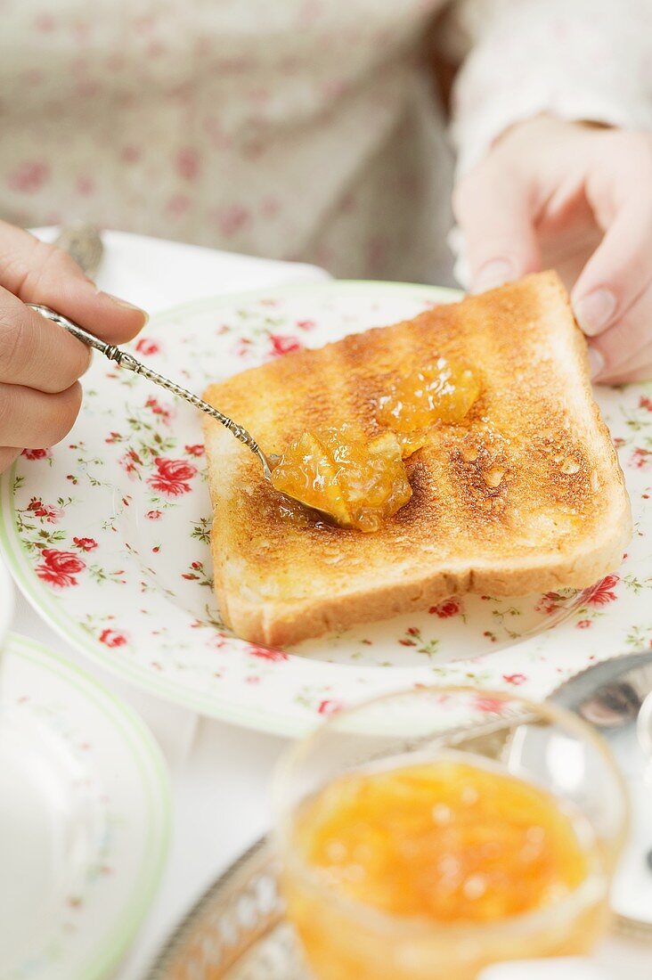 Toast mit Orangenmarmelade bestreichen