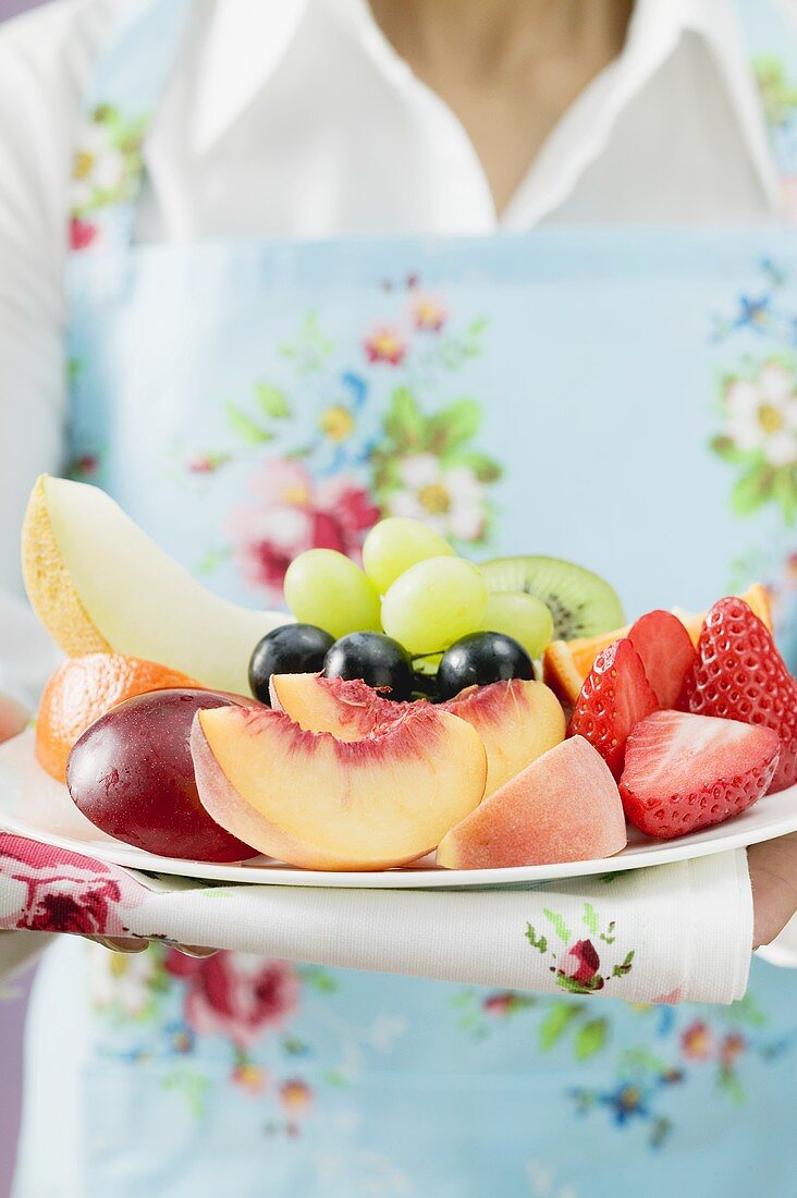 Woman serving a plate of fresh fruit
