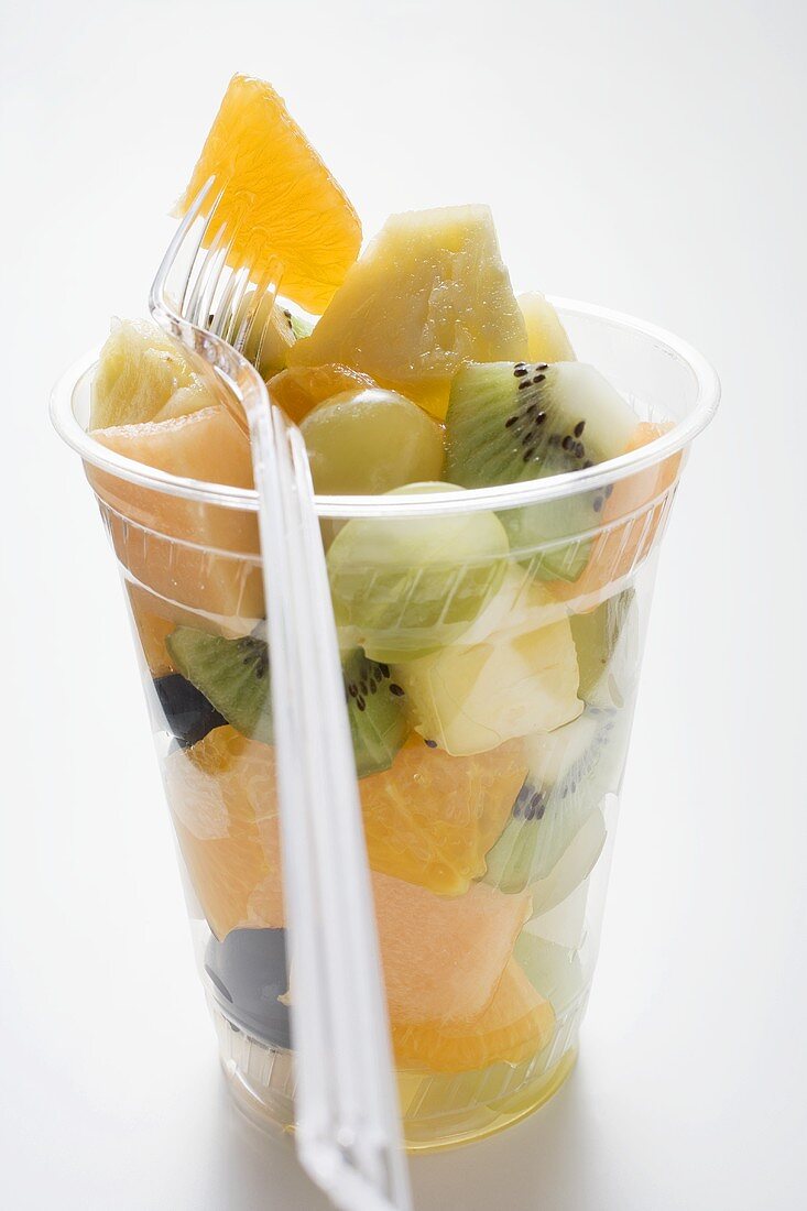 Fruit salad in a plastic beaker with a fork