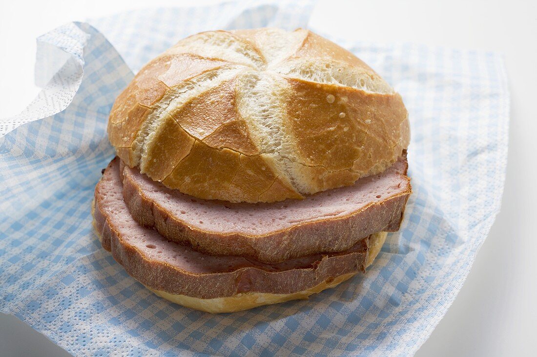Slices of Leberkäse (type of meatloaf) in a roll on paper napkin