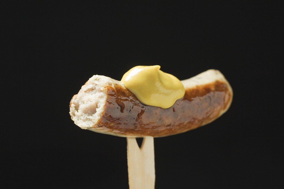 Sausage with mustard on wooden fork