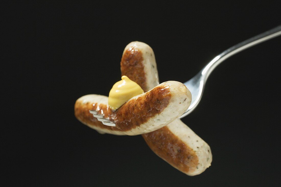 Sausages with mustard on fork