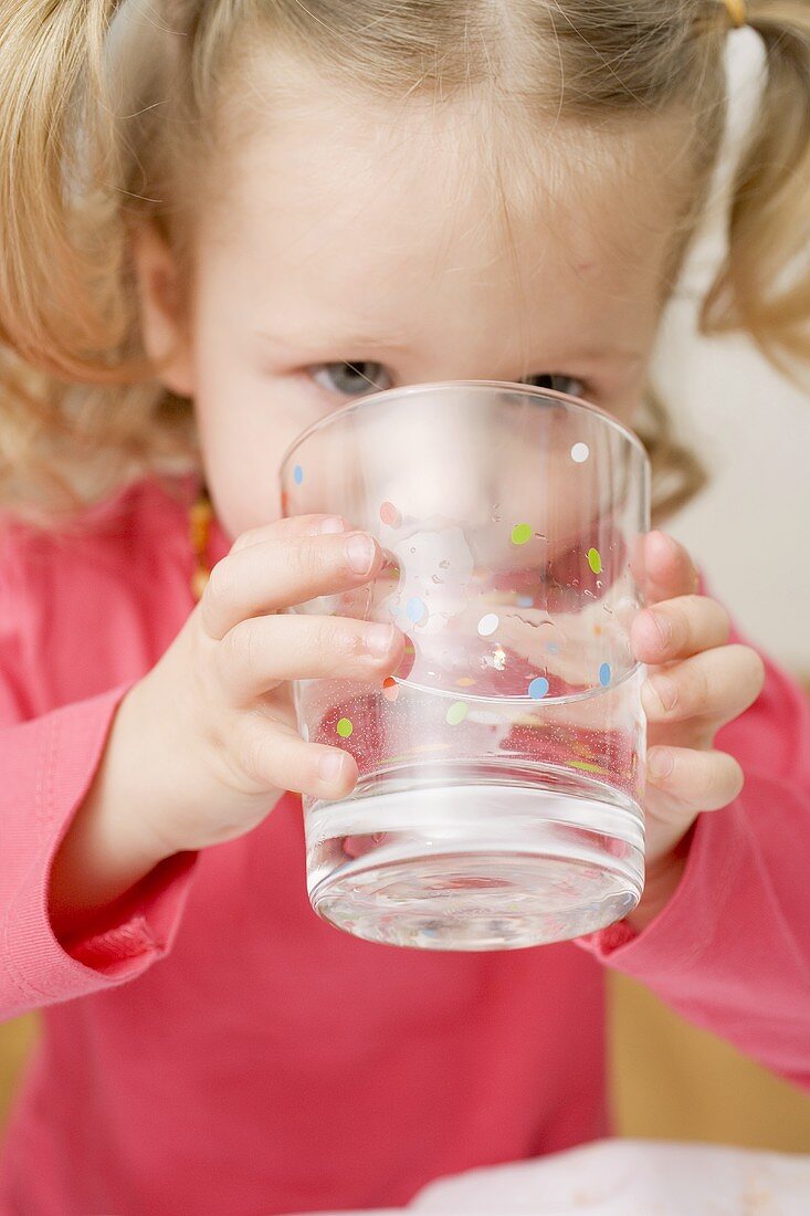Kleines Mädchen trinkt Glas Wasser