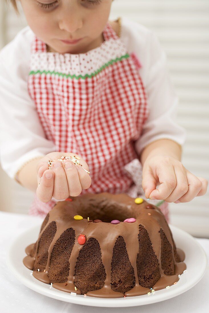 Small boy decorating ring cake with coloured chocolate beans