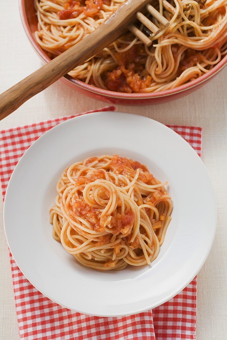 Spaghetti mit Tomatensauce auf Teller und in Schüssel
