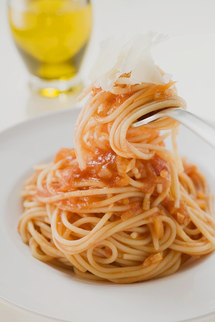 Spaghetti mit Tomatensauce und Parmesan auf Gabel und Teller