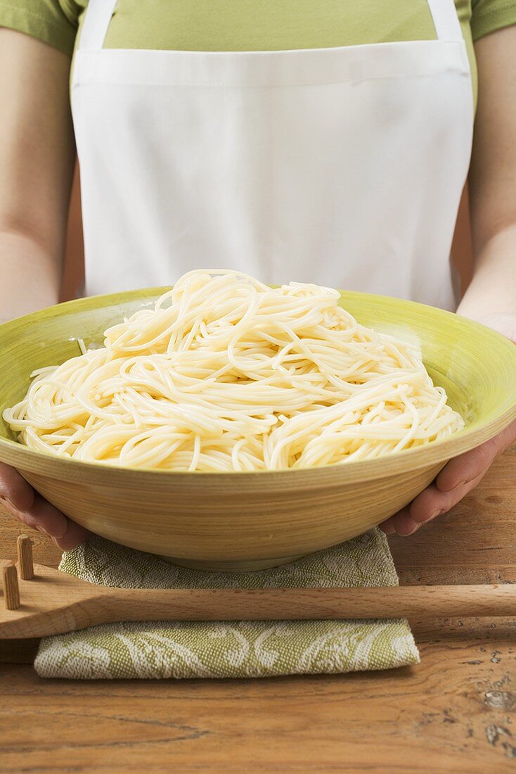 Frau hält Schüssel mit gekochten Spaghetti
