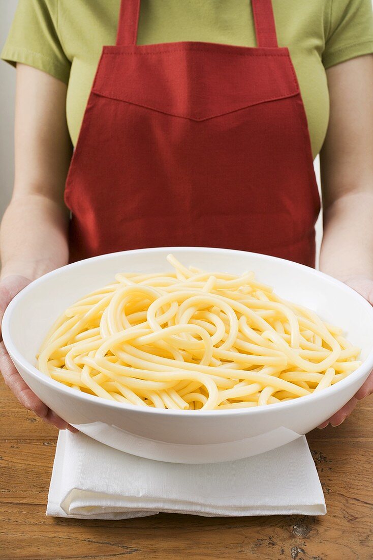 Woman holding bowl of cooked macaroni