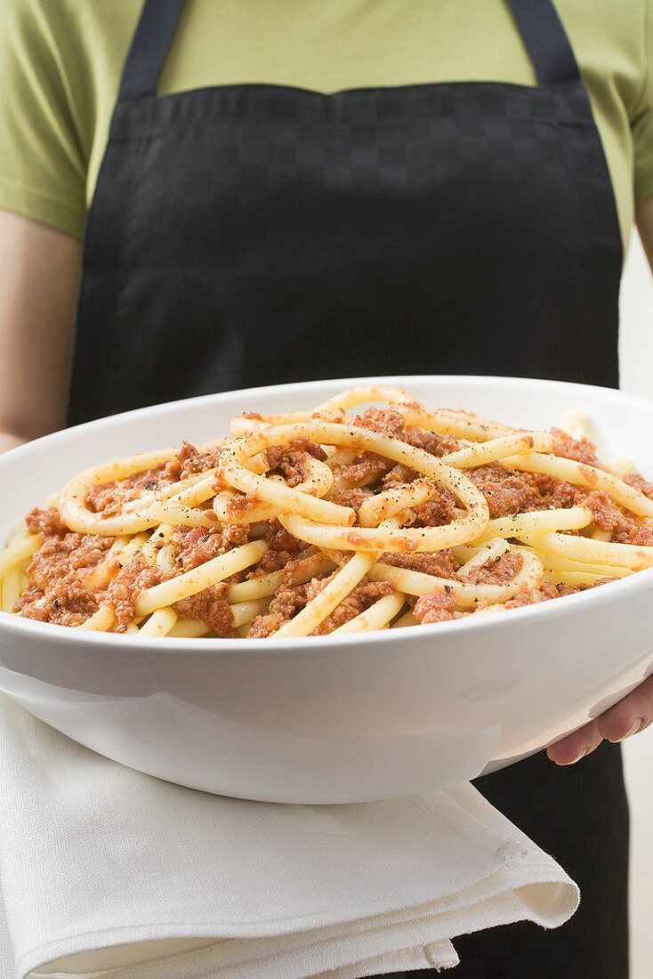 Person holding bowl of macaroni with mince sauce