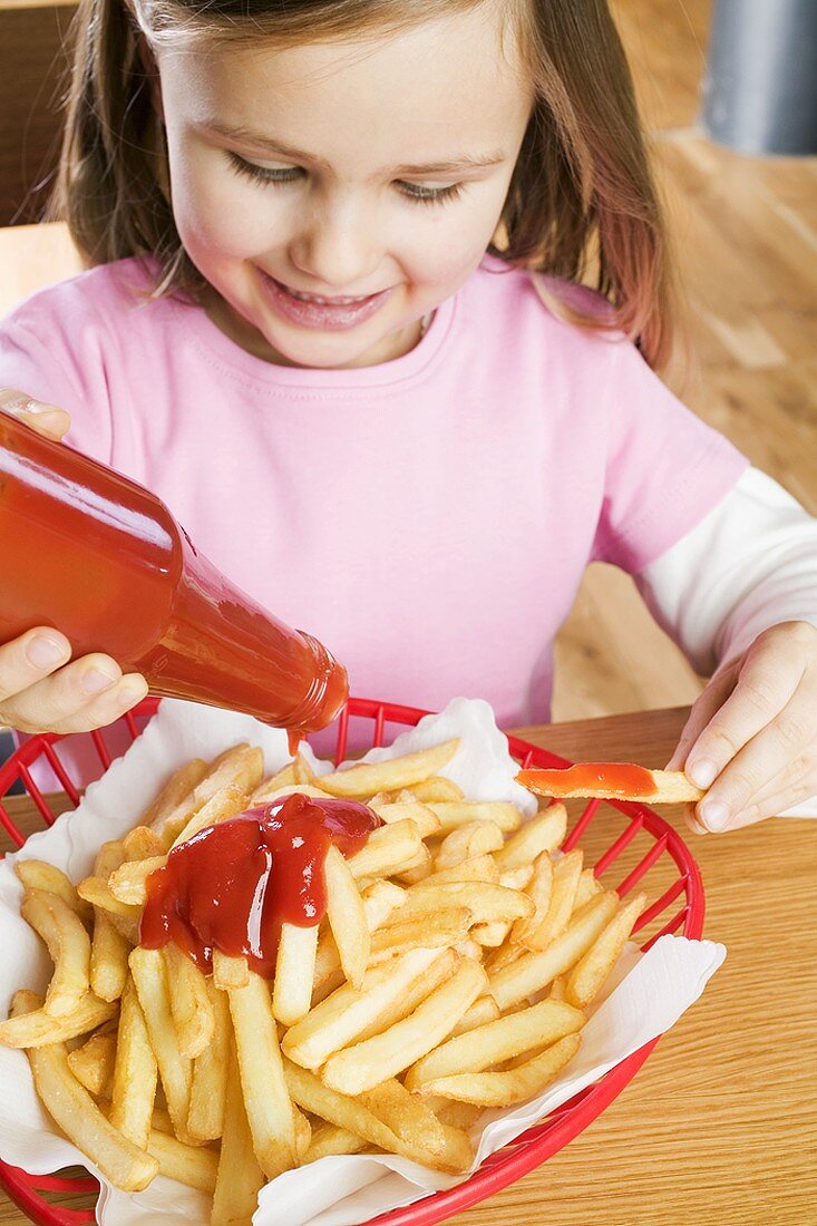 Mädchen schüttet Ketchup auf Pommes frites