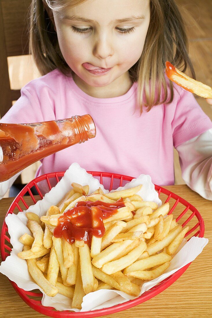 Mädchen isst Pommes frites mit Ketchup