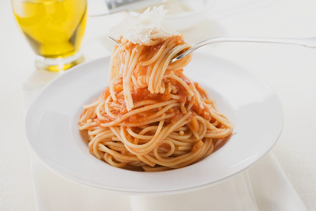 Spaghetti mit Tomatensauce und Parmesan auf Gabel und Teller