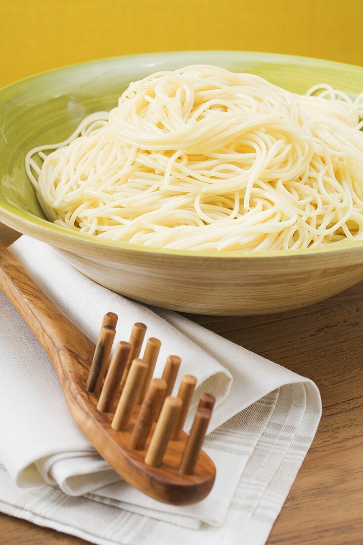 Gekochte Spaghetti in Schüssel, daneben Spaghettiheber