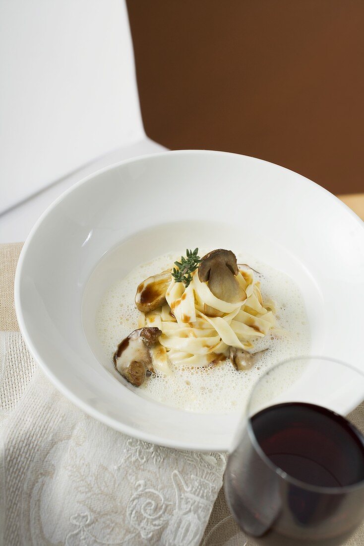 Ribbon pasta with ceps and cream sauce, glass of red wine