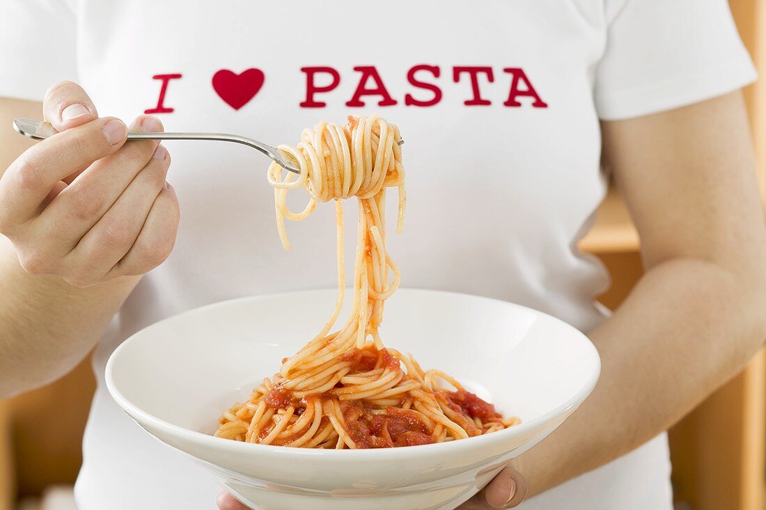 Woman eating spaghetti with tomato sauce