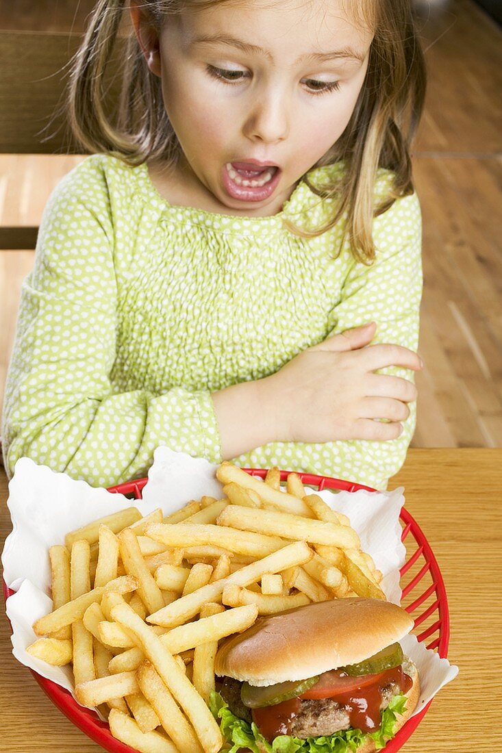 Horrified girl looking at hamburger and chips