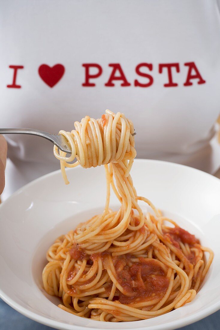 Woman eating spaghetti with tomato sauce