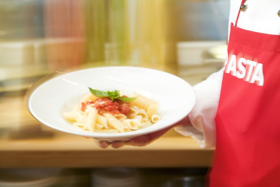 Chef serving penne with tomato sauce