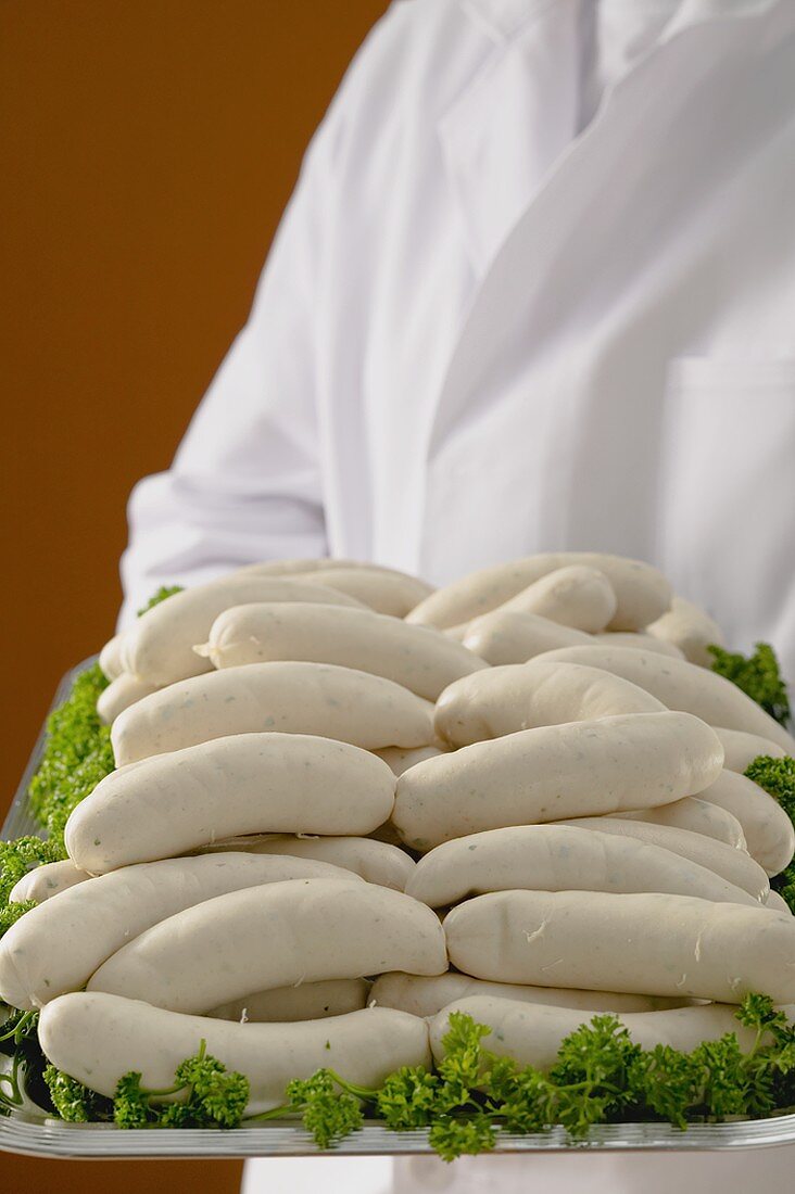 Person hält Tablett mit vielen Weisswürsten