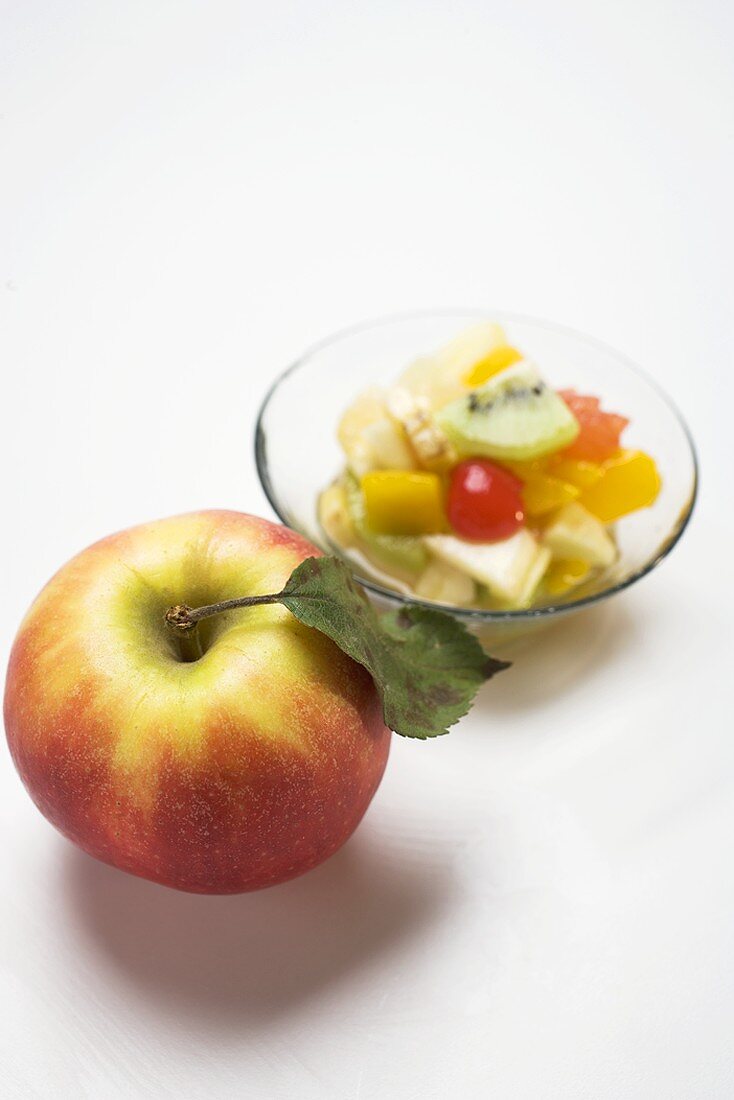 Frischer Apfel, Fruchtsalat im Hintergrund