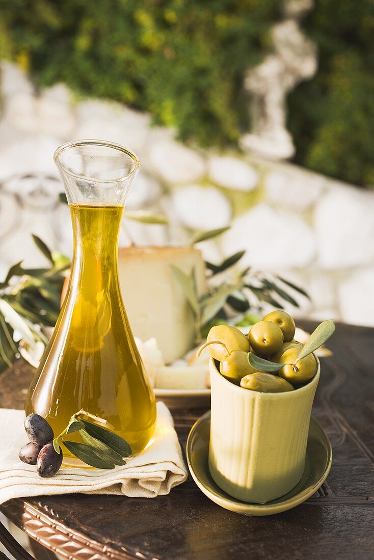 Oliven, Olivenöl, Käse und Cracker auf Tisch im Freien