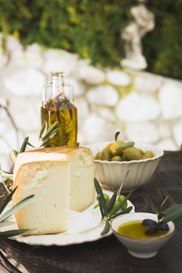 Käse, Oliven und Olivenöl auf Tisch im Freien