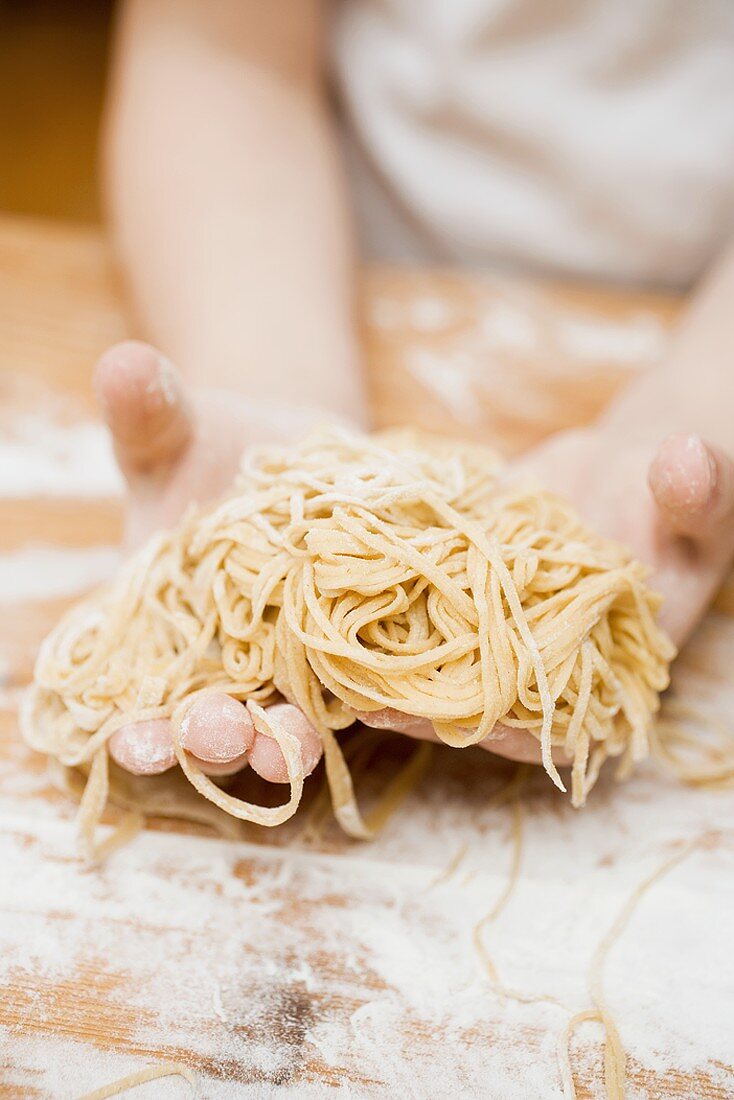 Kinderhände halten selbstgemachte Linguine