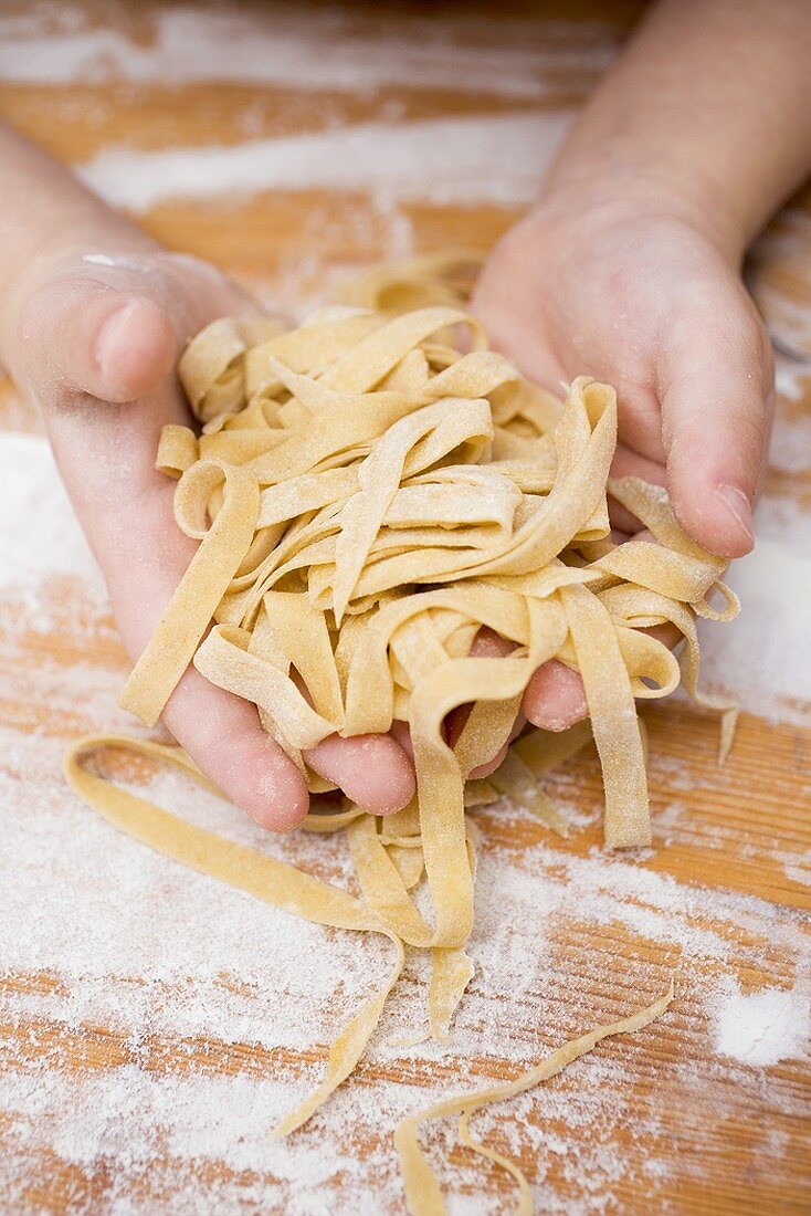 Child's hands holding home-made ribbon pasta