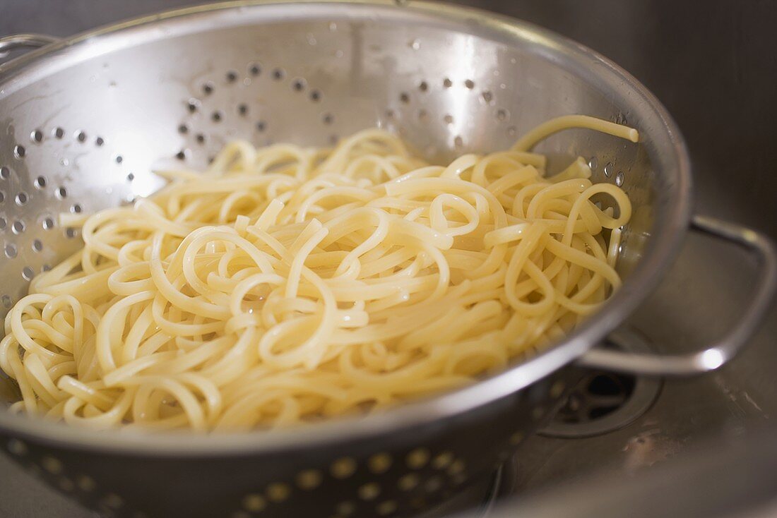 Draining cooked ribbon pasta in a colander